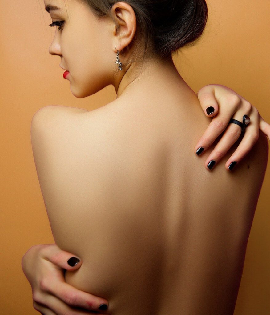 Nude female with her back to the camera, hugging herself